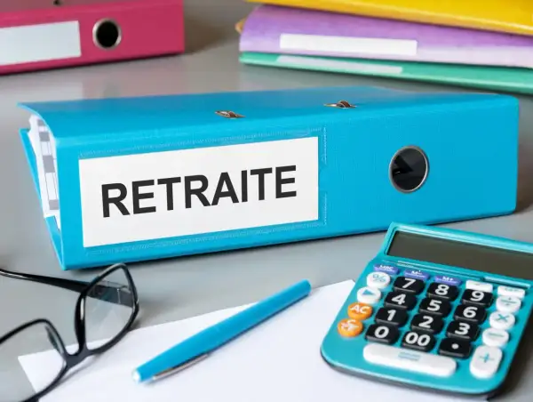 Dossier bleu "Retraite" sur un bureau, avec une calculatrice, des lunettes et un stylo. L'aspa montant est peut-être dans ce dossier.