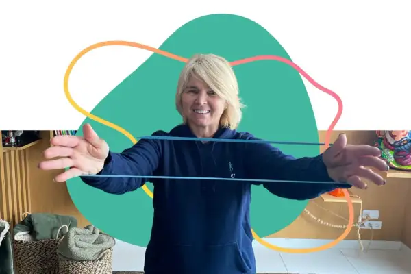 Une femme souriante fait des exercices avec un élastique, parfaite pour un programme de mise en forme 60 ans et plus.