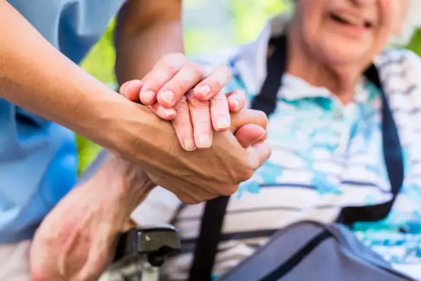 Une main plus jeune tient une main âgée. L'âge limite pour être tuteur est une question importante pour assurer le bien-être des personnes vulnérables.