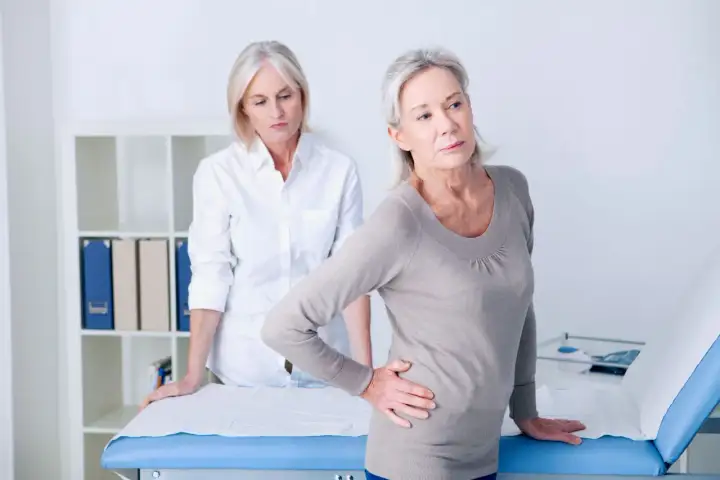 Une femme souffre de douleurs à la hanche, possiblement liées à l'arthrose. Une autre femme, peut-être une professionnelle de santé, l'observe. La musculation pourrait aider.